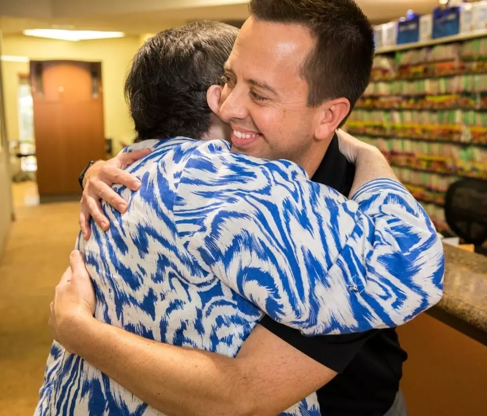 Matthew R. Burton, DMD hugging a patient after helping her achieve her smile goals